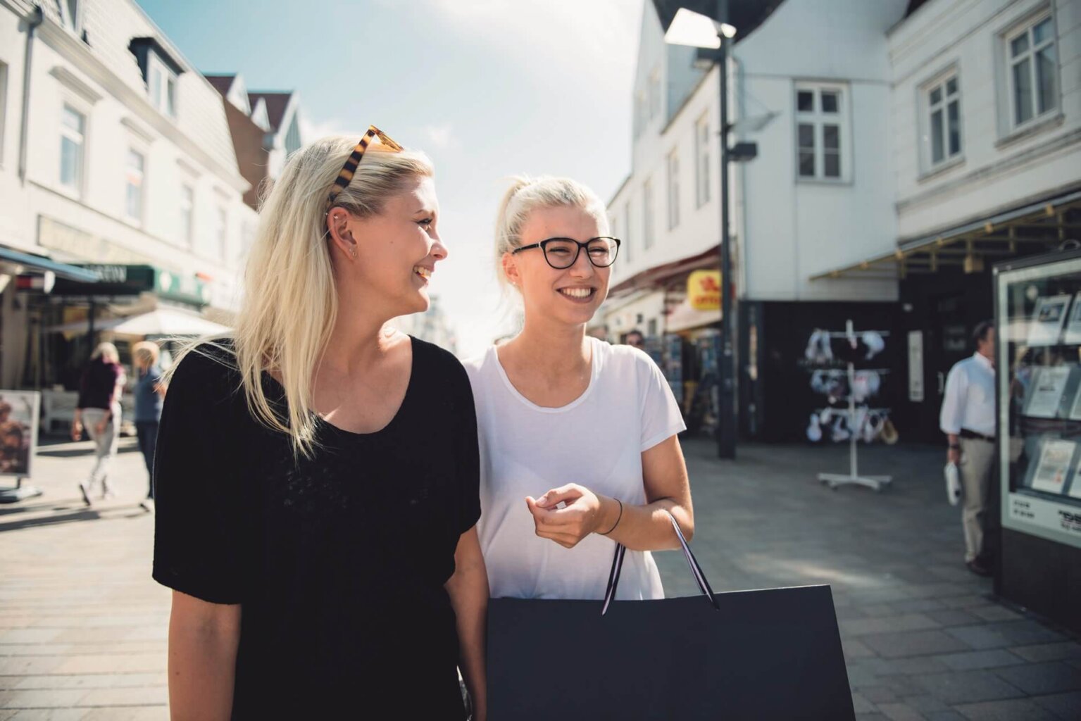 Kurzurlaub auf Sylt - Zwei Frauen gehen shoppen in der Einkaufsstraße von Westerland. Die Sonne scheint und die beiden lachen zusammen.